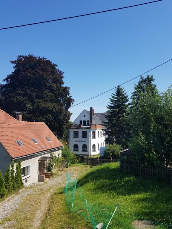 une grande maison blanche sur une colline herbeuse dans l'établissement Gasthof Oberschmiede, à Auf der Wiese