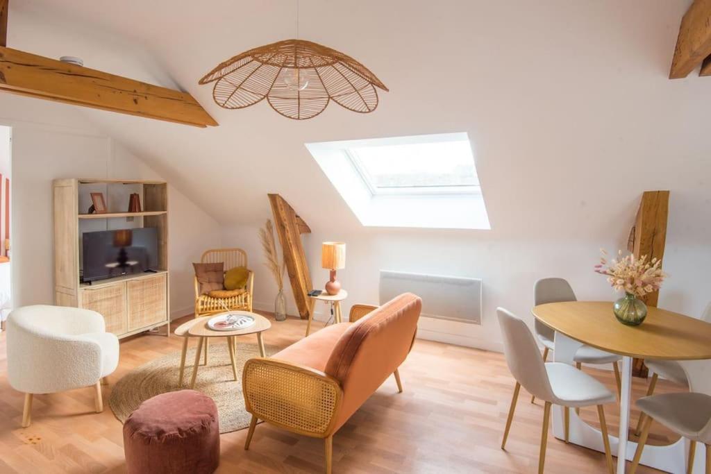 een woonkamer met stoelen en tafels en een dakraam bij L'appartement Bohême in Angers