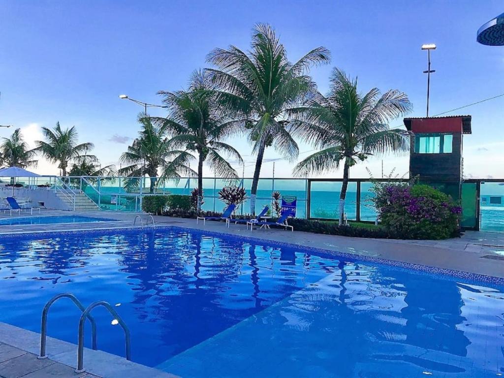 una gran piscina con palmeras y el océano en Sonia Flats Natal - No Apart Hotel Ponta Negra Beach, en Natal