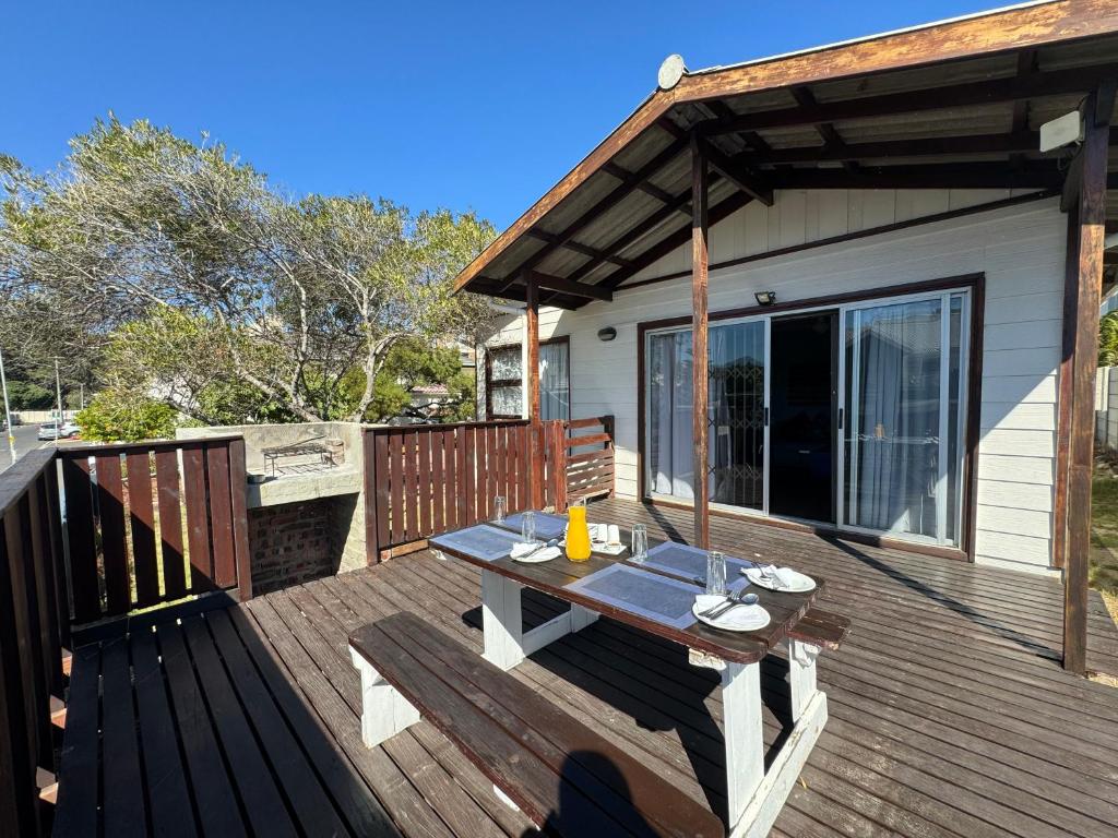 a wooden deck with a picnic table on it at Loddeys Beach House in Strand