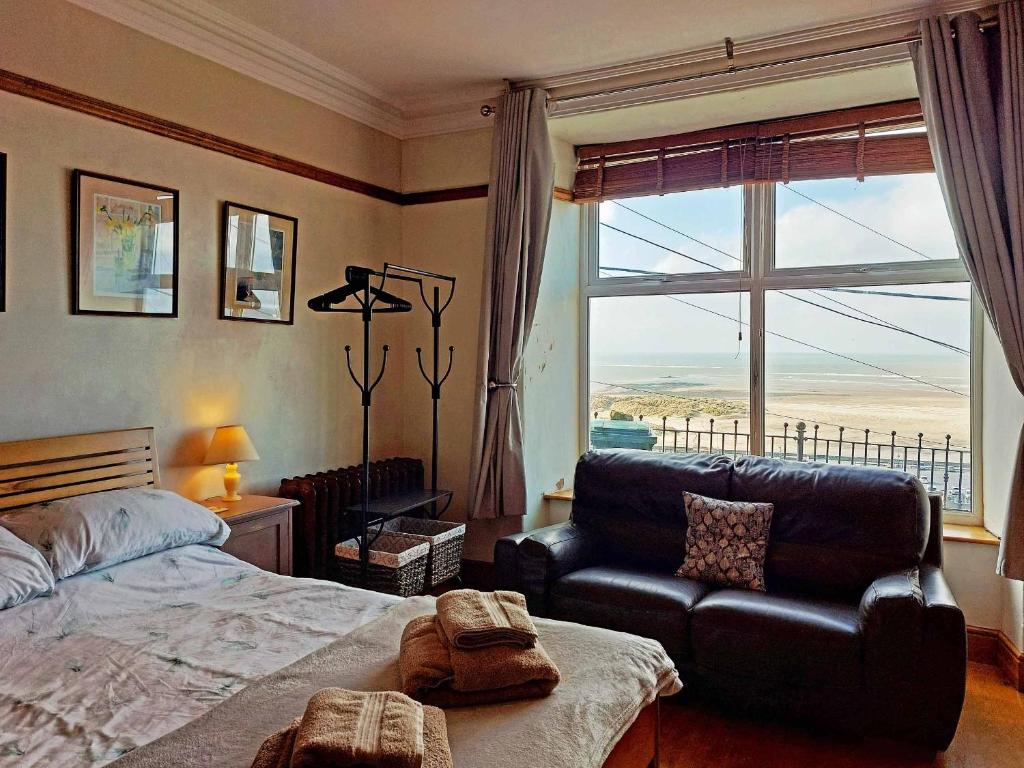 a bedroom with a bed and a couch and a window at High View Studio with terrace & sea views in Barmouth