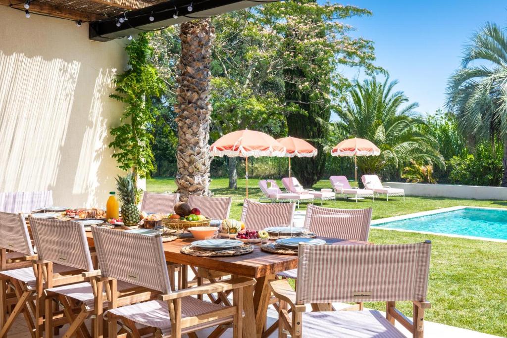 une table et des chaises en bois ainsi qu'une piscine dans l'établissement Villa Toscane, à Saint-Tropez