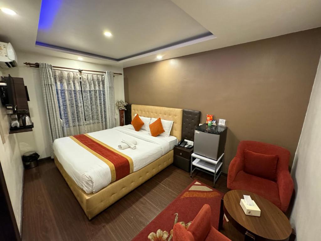 a hotel room with a bed and a chair at Marinha Airport Hotel in Kathmandu