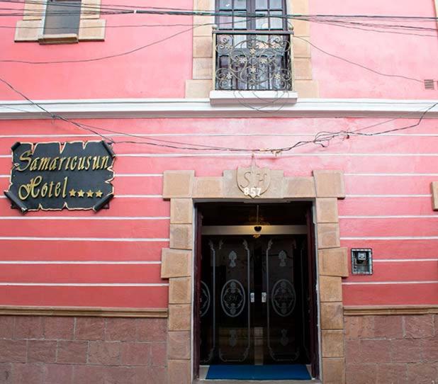 ein rosafarbenes Gebäude mit einer schwarzen Tür vorne in der Unterkunft HOTEL SAMARICUSUN in Potosí
