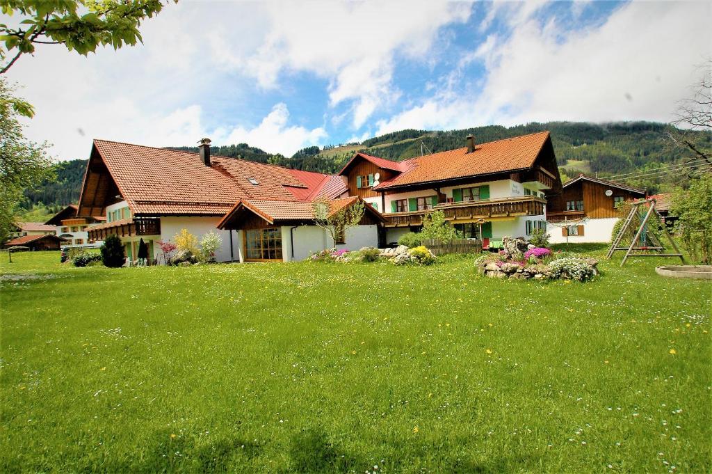 ein großes Haus auf einem grünen Rasen in der Unterkunft Ferienhof 'beim Wendlar' in Bad Hindelang