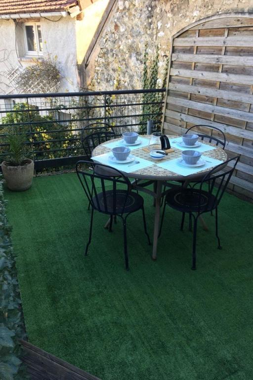 une table et des chaises sur une terrasse avec de l'herbe verte dans l'établissement Les Agapanthes, à Vernon