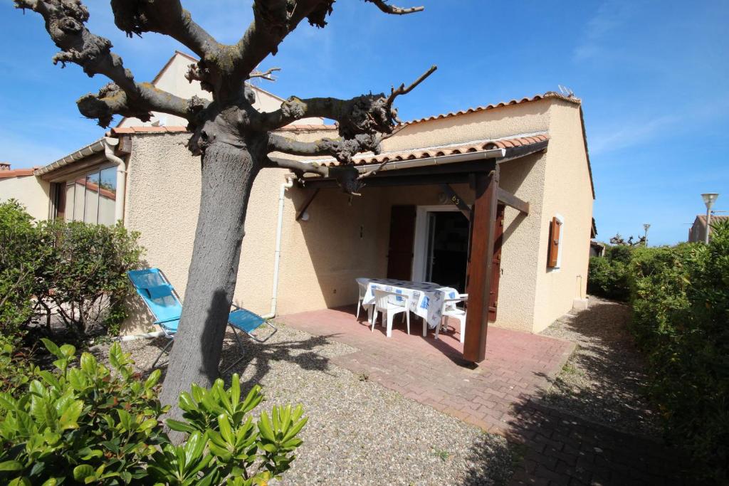 une maison avec une table et des chaises devant dans l'établissement 300m de la plage, adorable maison 2 chambres 4-6 couchages terrasse parking privatif LRSEN63, à Portiragnes