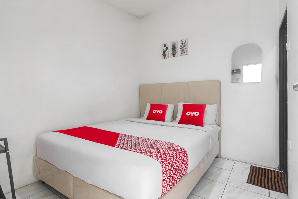 a bedroom with a bed with two red pillows at OYO 93720' 3D Residence Near Univ Tarumanegara in Jakarta