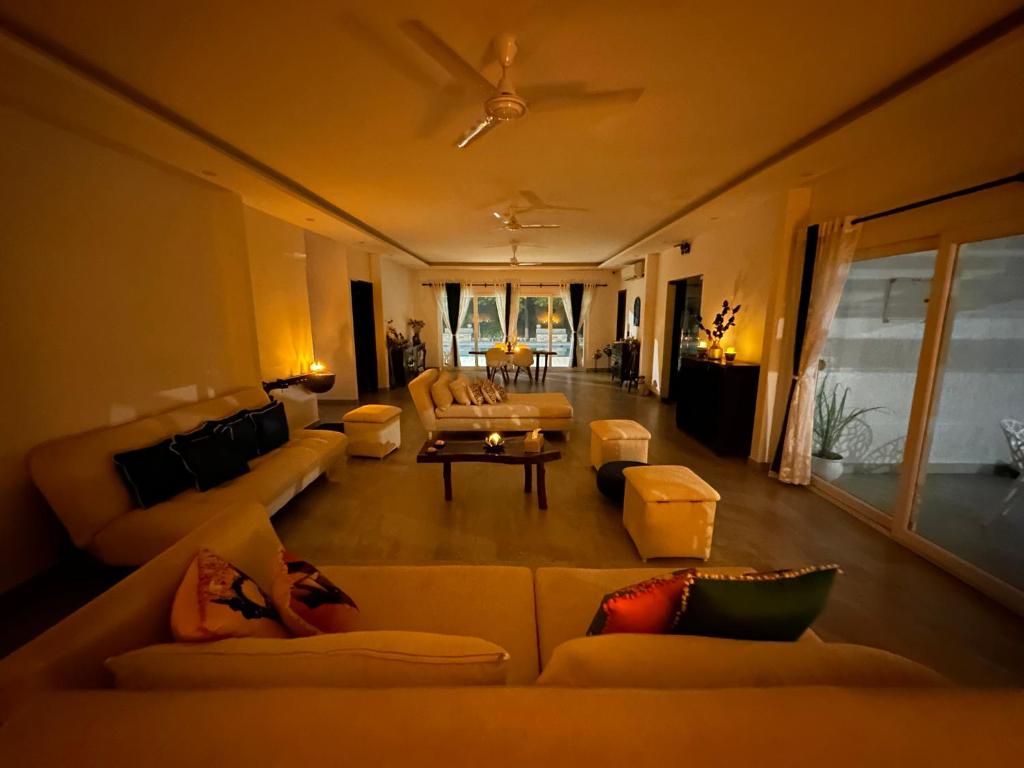 a living room with couches and a person laying on a couch at Luxurious Farmhouse with Pool outside Delhi in Noida