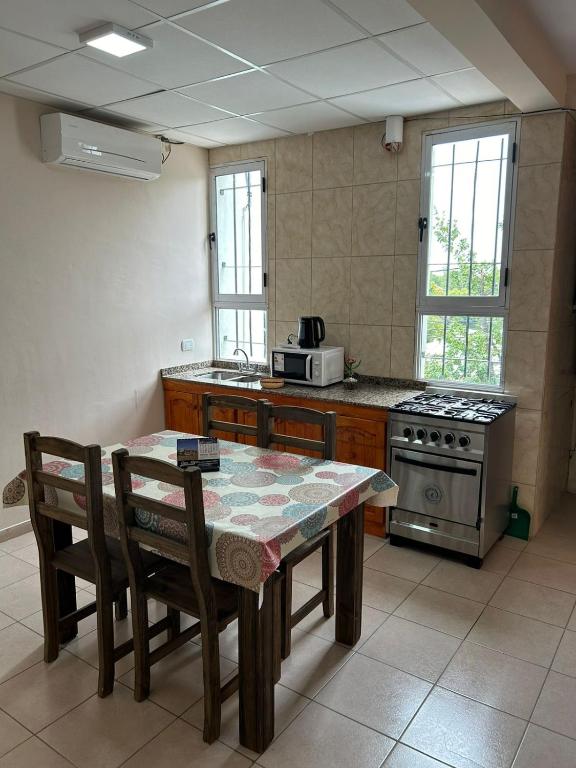 a kitchen with a table with chairs and a stove at Apartamentos El Viñedo 8 in General Alvear
