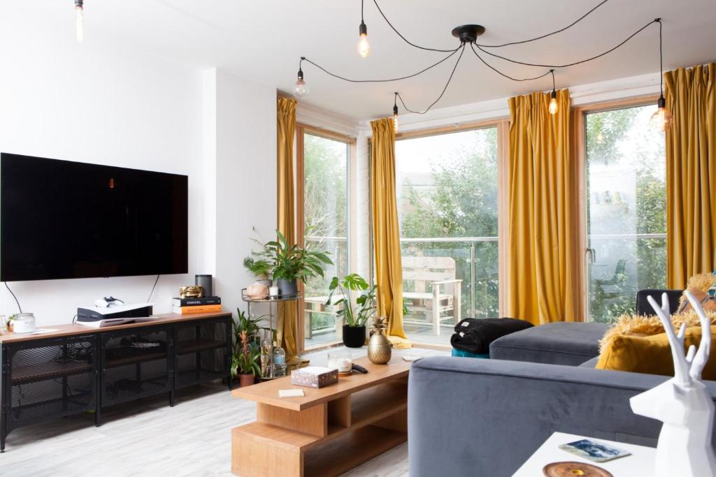 uma sala de estar com um sofá azul e uma televisão de ecrã plano em GuestReady - Lush moderno perto do Queen's Park em Brighton & Hove
