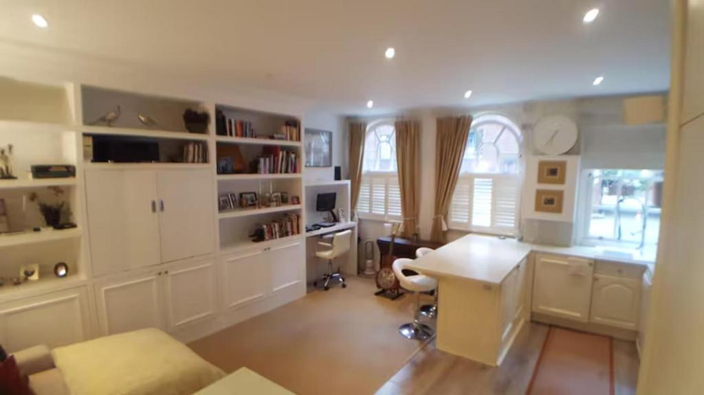 a kitchen with white cabinets and a desk in a room at Spacious luxury central London 1-bed apartment in London