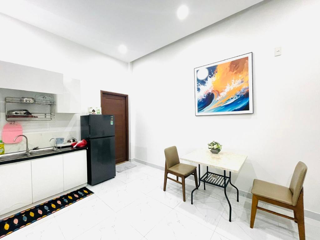 Il comprend une cuisine équipée d'une table et d'un réfrigérateur noir. dans l'établissement Tina Homestay 2 Đà Nẵng, à Đà Nẵng