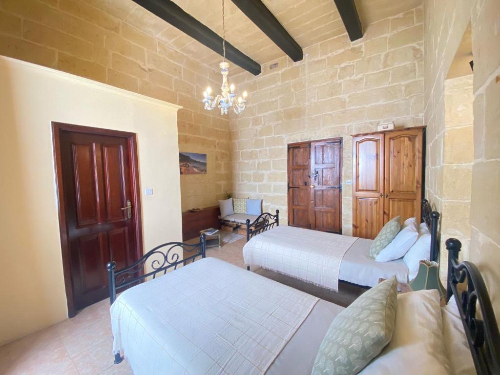 a bedroom with two beds and a chandelier at A la maison B&B in Xagħra