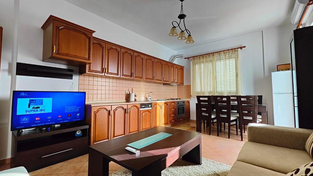 a kitchen with wooden cabinets and a living room at Appartamento Bruno spazioso e centrale in Shkodër