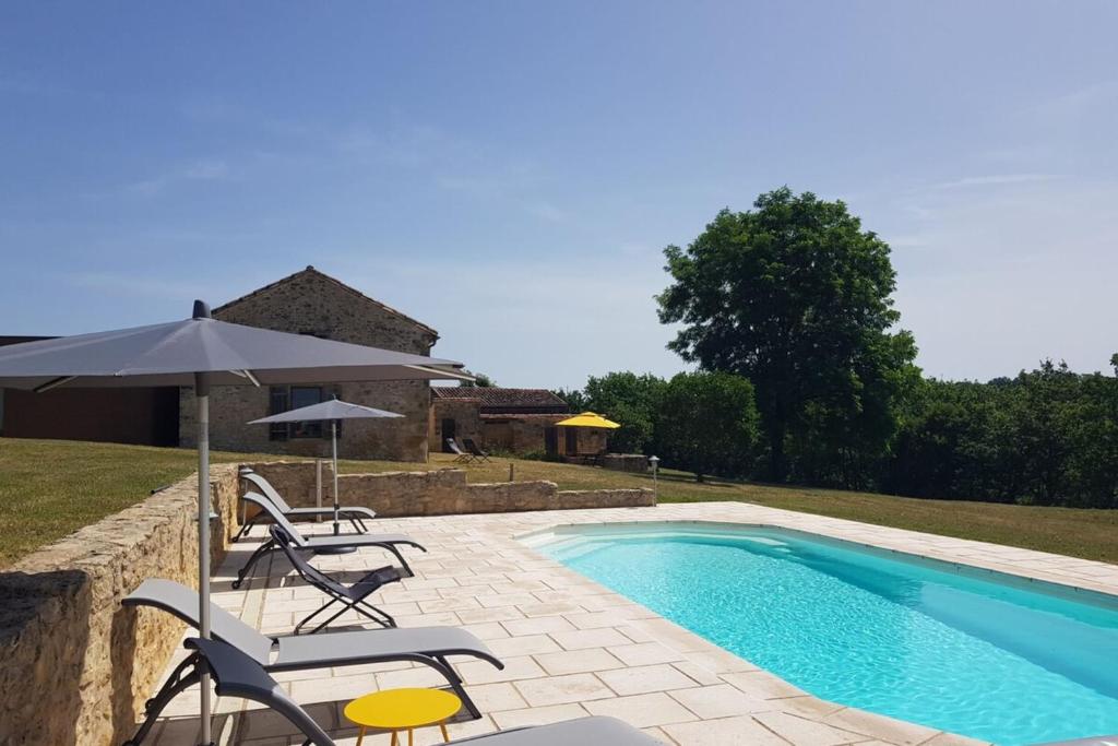 - une piscine bordée de chaises et d'un parasol dans l'établissement Chez François- Charme & Authenticité - Piscine - Climatisation, à Saint-Avit-Sénieur