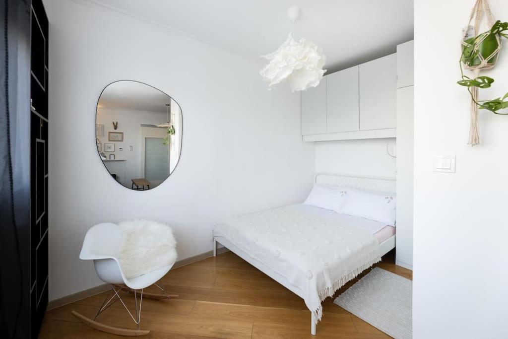 a white bedroom with a mirror and a white chair at cozinesT eco apartment in Zagreb