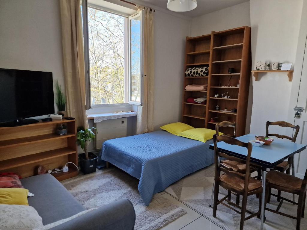 a bedroom with a bed and a table and a tv at Apartment close to Lyon and Parc de Parilly in Saint-Priest