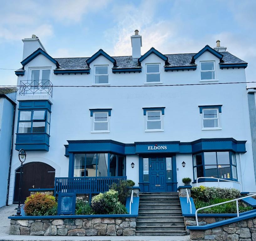 uma grande casa branca com portas azuis e escadas em Eldon's Bed & Breakfast em Roundstone