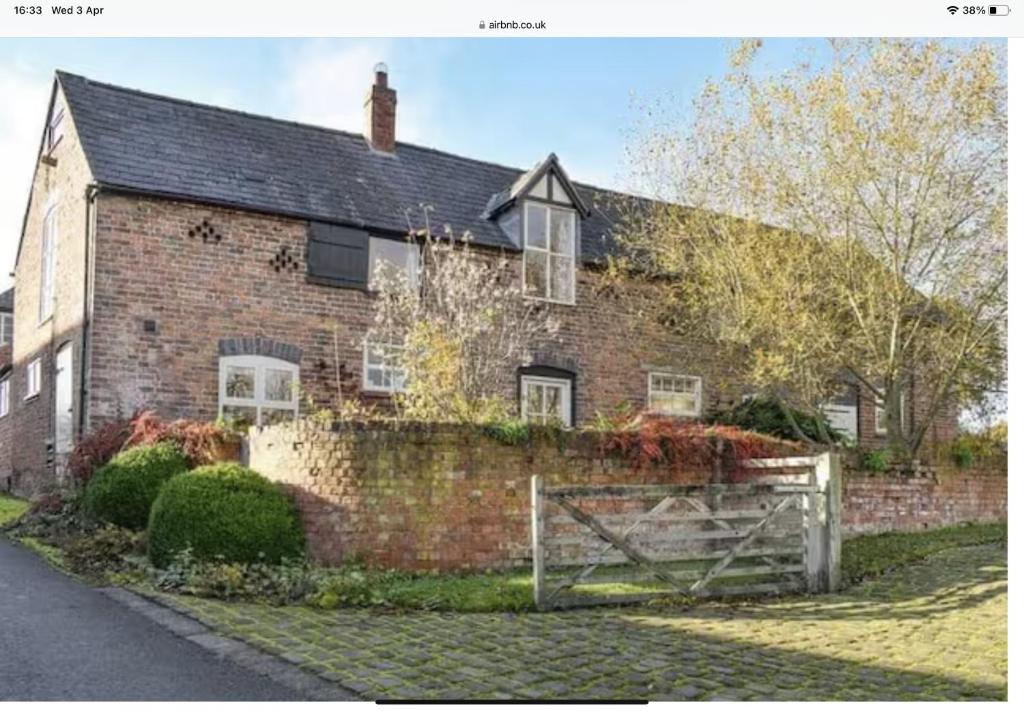 a brick house with a fence in front of it at The Coach House Annex in Tilston