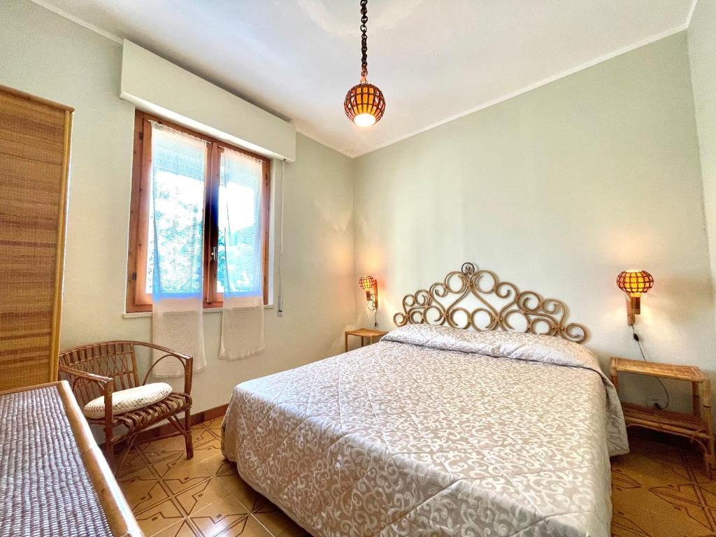 een slaapkamer met een bed, een stoel en een raam bij Villa Marina con piscina sul mare in Platamona