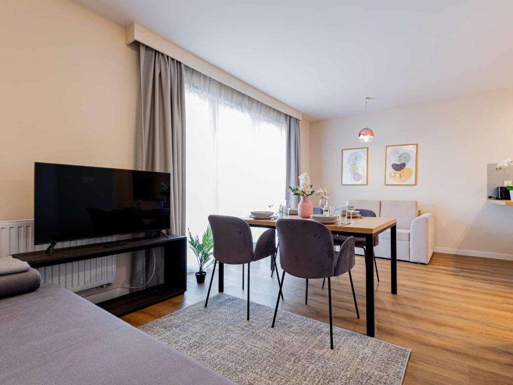 a living room with a table with chairs and a television at VacationClub - Apartamenty Zakopiańskie Apartament 141 in Zakopane