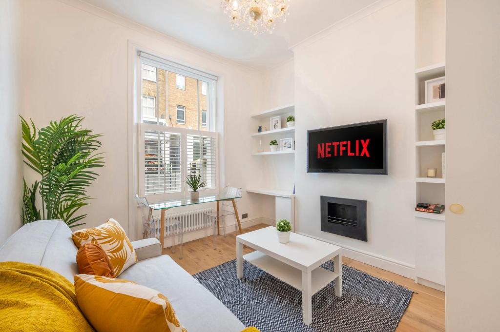 a living room with a couch and a tv at Charming 1 Bedroom Flat with Private Patio - West London, Kensington, Earl's Court, Chelsea in London