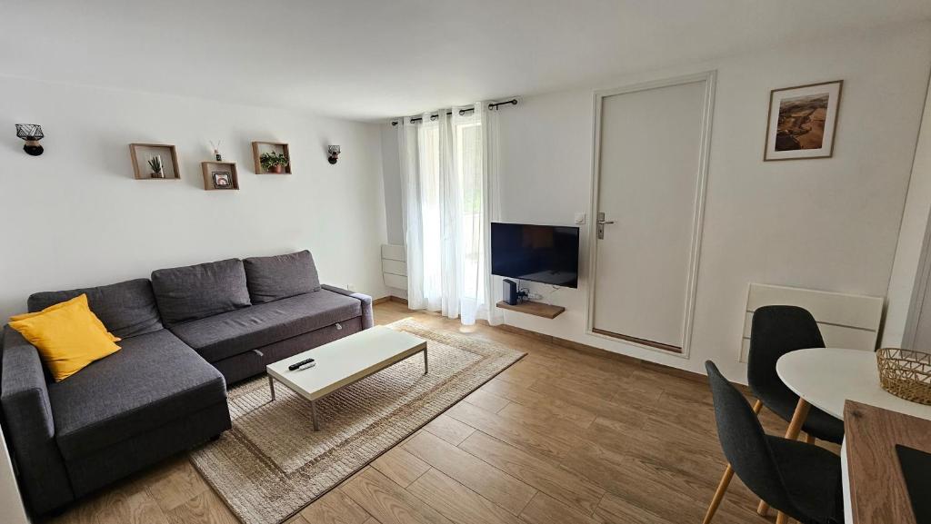 a living room with a couch and a table at CosyNook - refait à neuf proche parc des expositions et aéroport CDG - Parking privé gratuit in Villepinte