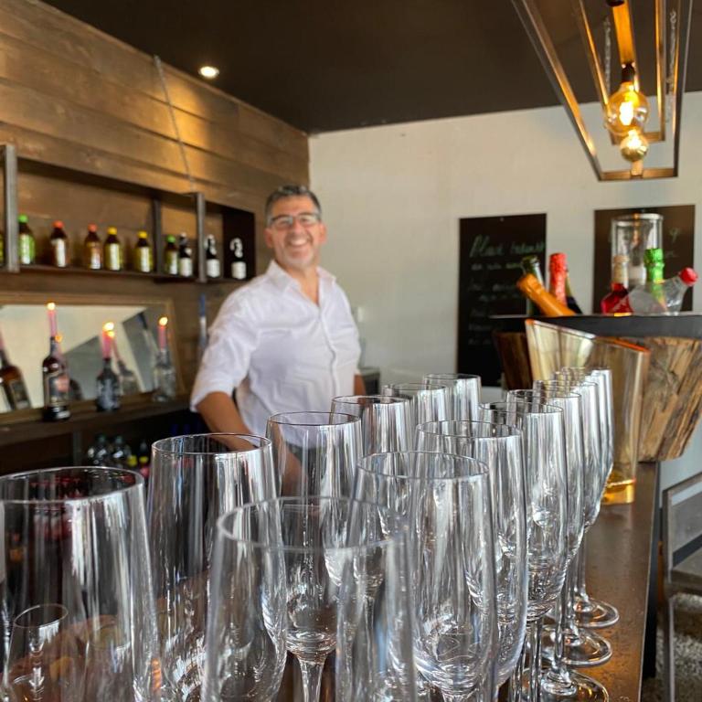 a man standing behind a counter with wine glasses at Familie &amp; Vriendenwoning met fantastisch uitzicht in Ellezelles