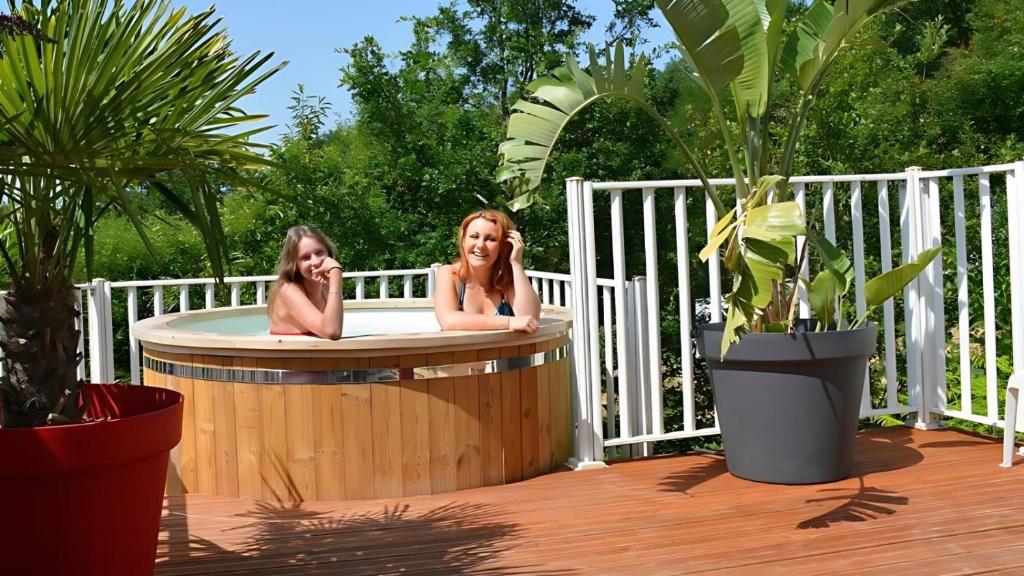 Duas raparigas sentadas numa banheira de hidromassagem num deque em Les Ventoulines em Domme