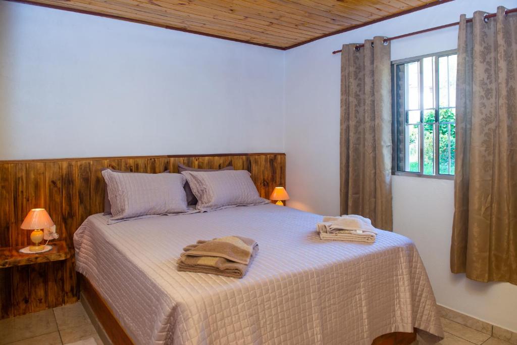 a bedroom with a bed with two towels on it at Chalés Cachoeira do Vale in Camanducaia