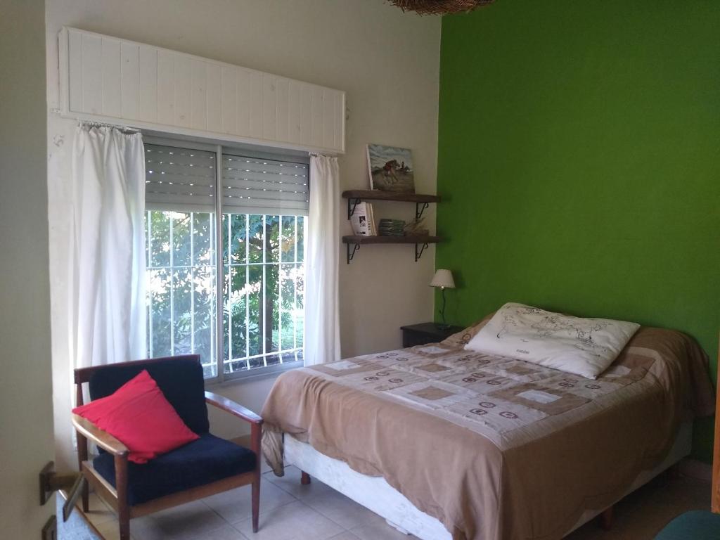 a green bedroom with a bed and a chair and a window at QUINTA LA LUISA in Villa Lía