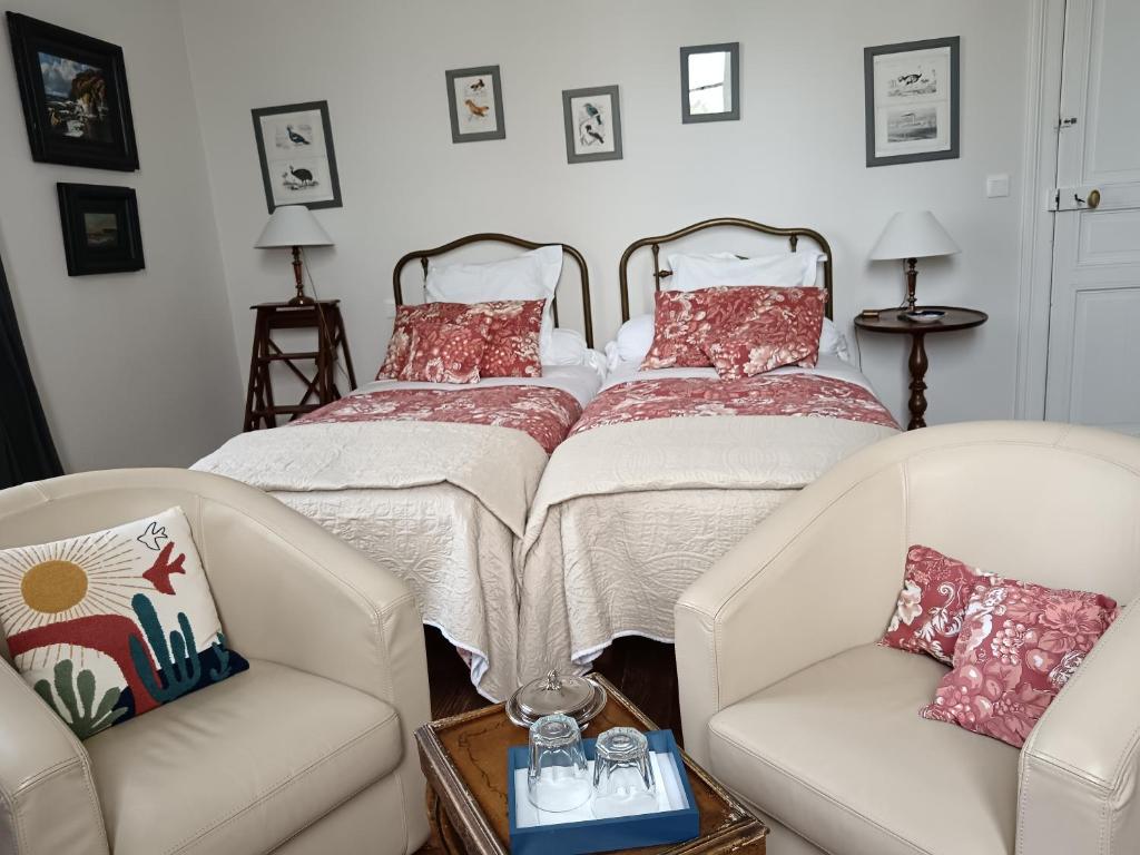 a living room with two chairs and a bed at Castel La Bergerie in Laglorieuse