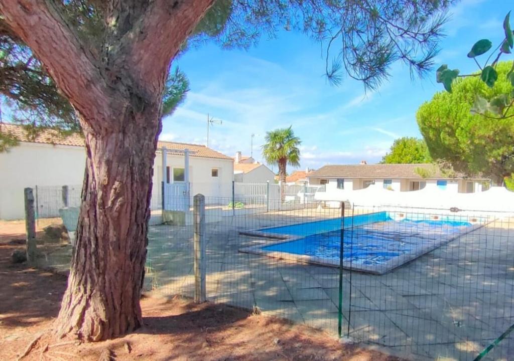 une clôture autour d'une piscine à côté d'un arbre dans l'établissement Villa du lagon avec piscine, à Saint-Michel-en-lʼHerm