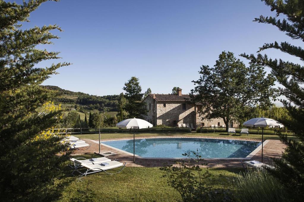 a pool with chairs and umbrellas in front of a house at Villa - Podere Monti in Sant'Albino