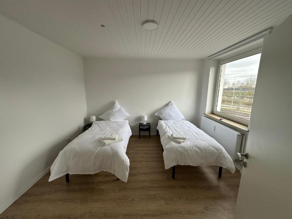 2 bedden in een witte kamer met een raam bij GuestHouse Bielefeld - Brackwede in Bielefeld