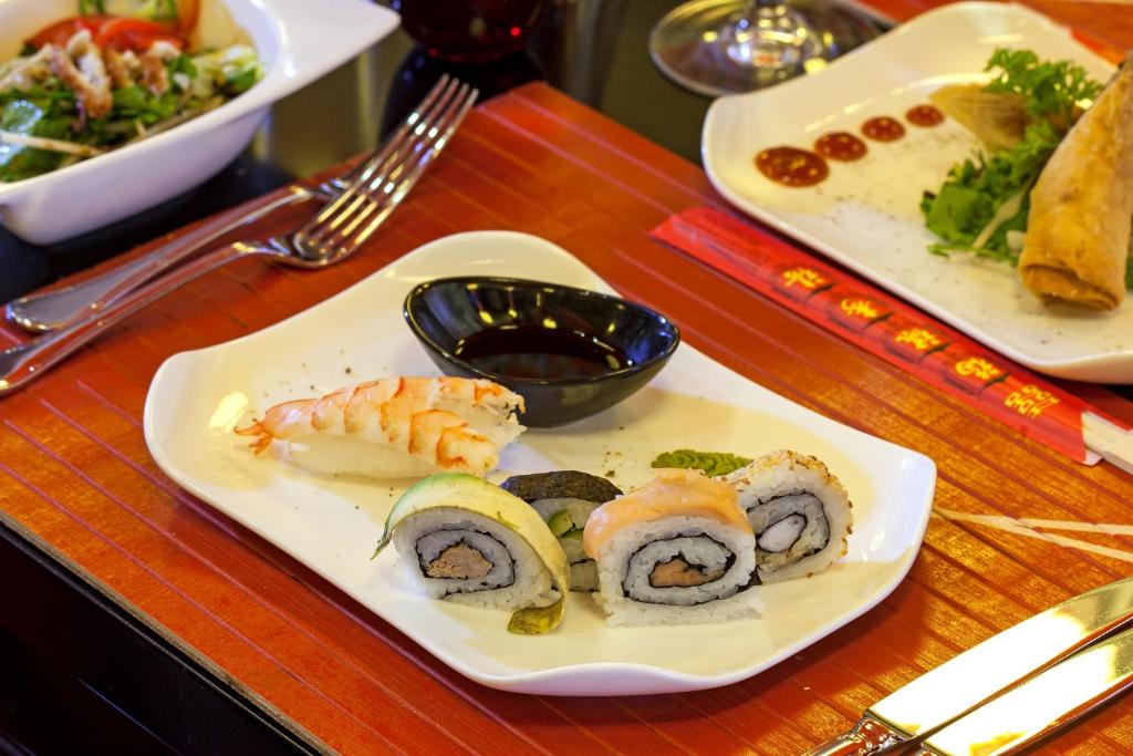 a table with plates of sushi and a bowl of sauce at Sherwood Exclusive Kemer - Kids Concept in Kemer