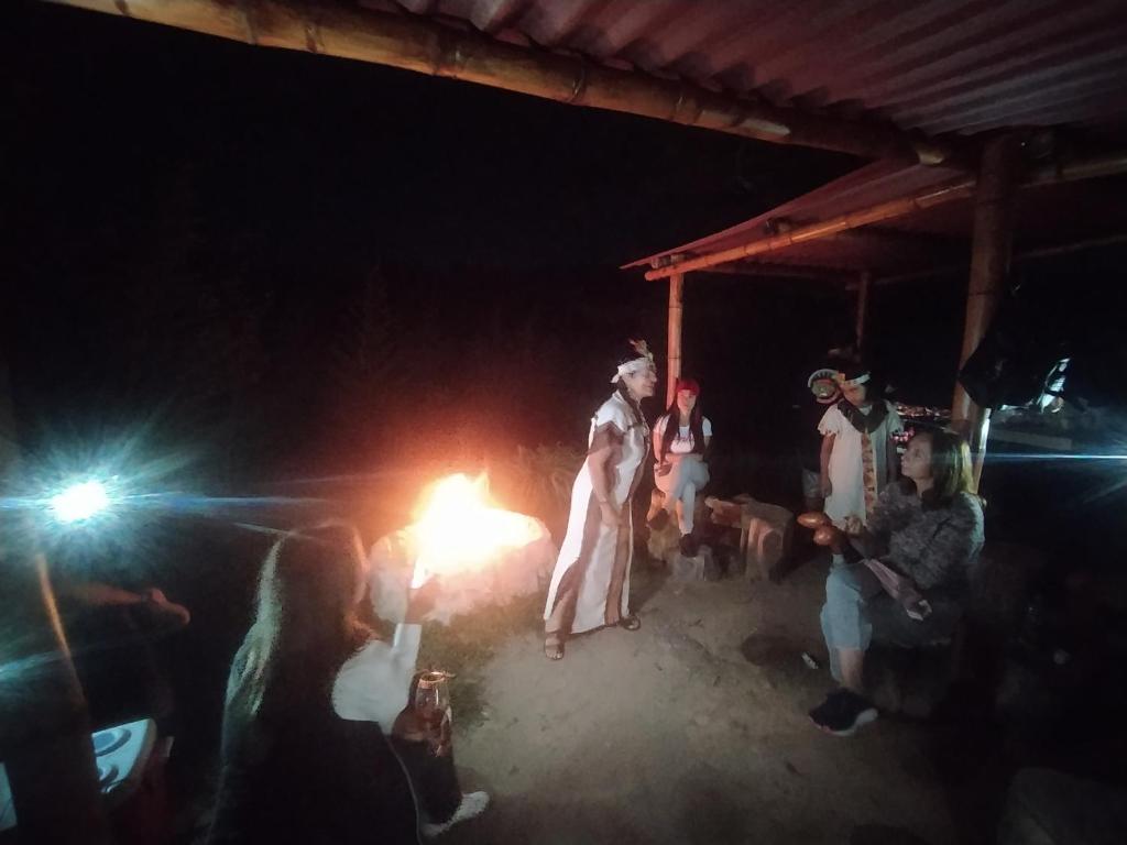 a group of people standing around a fire at night at Casa Encuentro Ecolodge, Outdoor Gym and Yoga in Guatapé