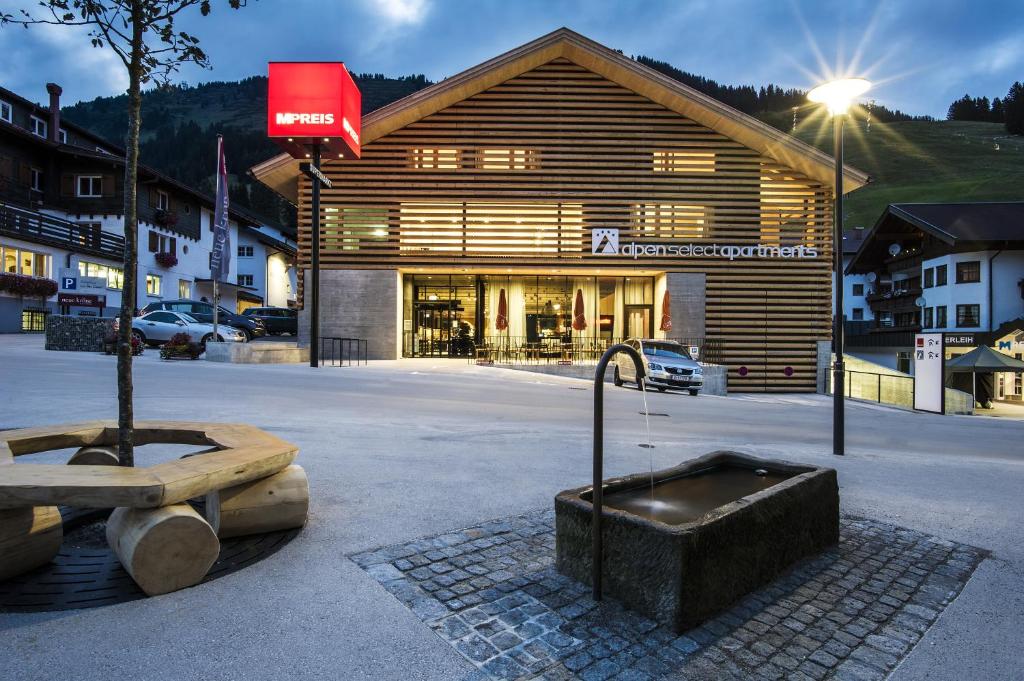 un edificio con una fontana di fronte ad esso di alpen select apartments Kleinwalsertal a Mittelberg