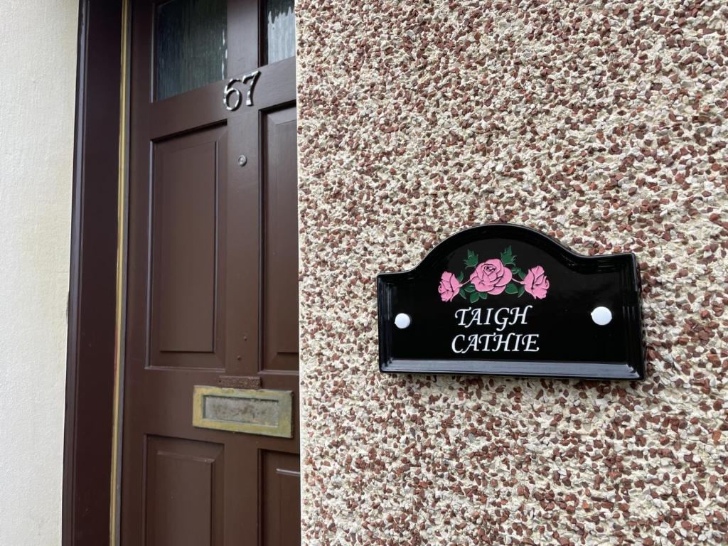 una señal en el lateral de un edificio al lado de una puerta en TAIGH CATHIE, 67 Alma Road, en Fort William