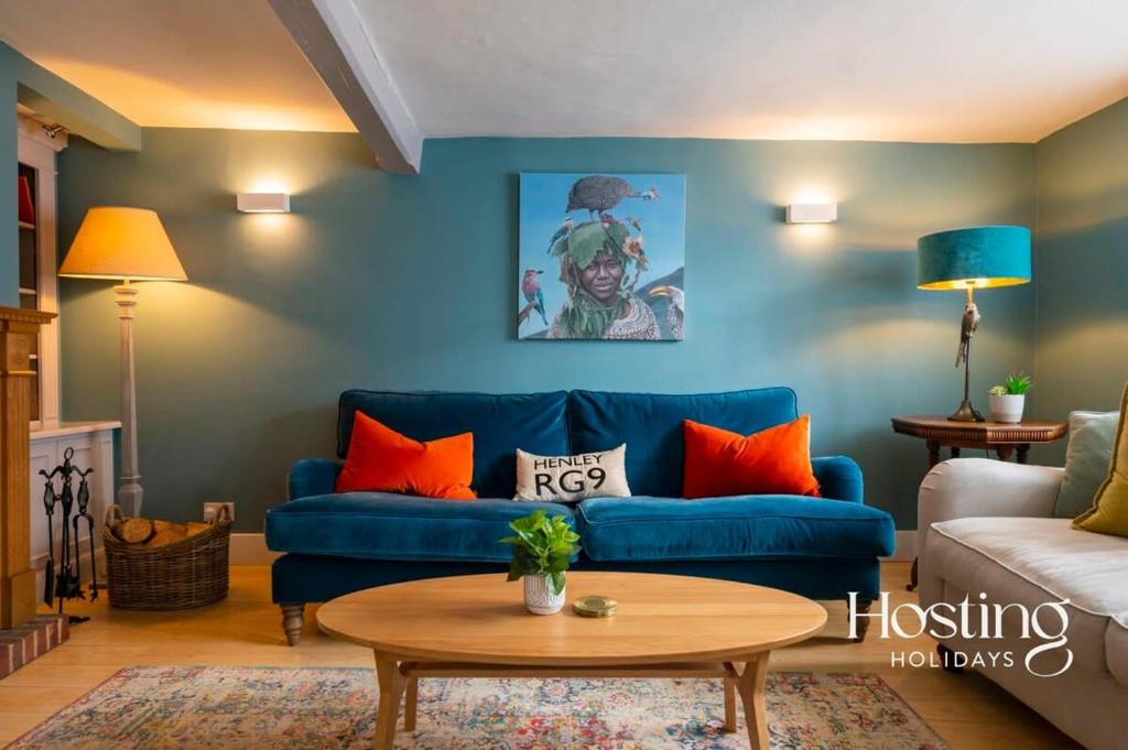 a living room with a blue couch and orange pillows at Spacious Luxury Cottage With Roof Terrace Close To The River Thames in Henley on Thames