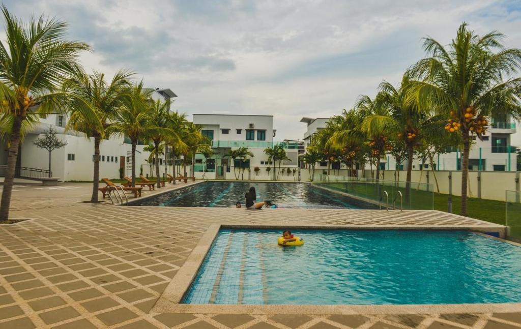 une piscine avec des palmiers et une personne dans un radeau dans l'établissement 8Pax comfortable setia residen, à Sitiawan