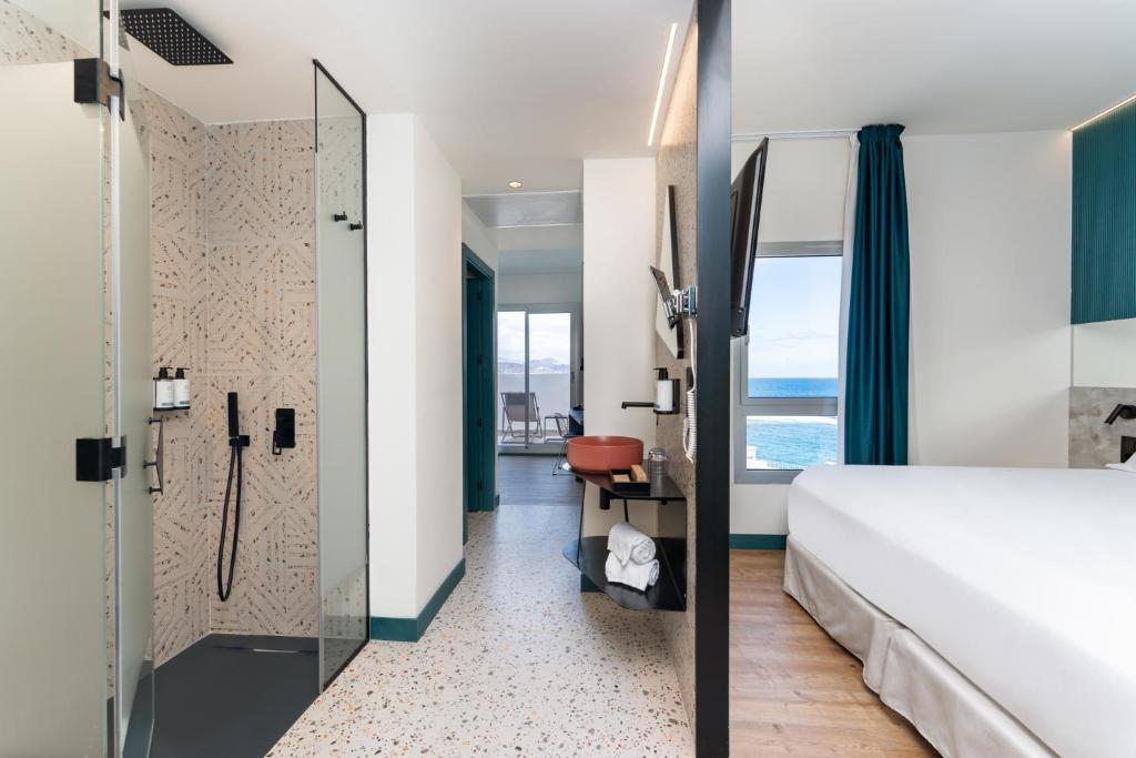 a hotel room with a bed and a shower at Occidental Las Canteras in Las Palmas de Gran Canaria