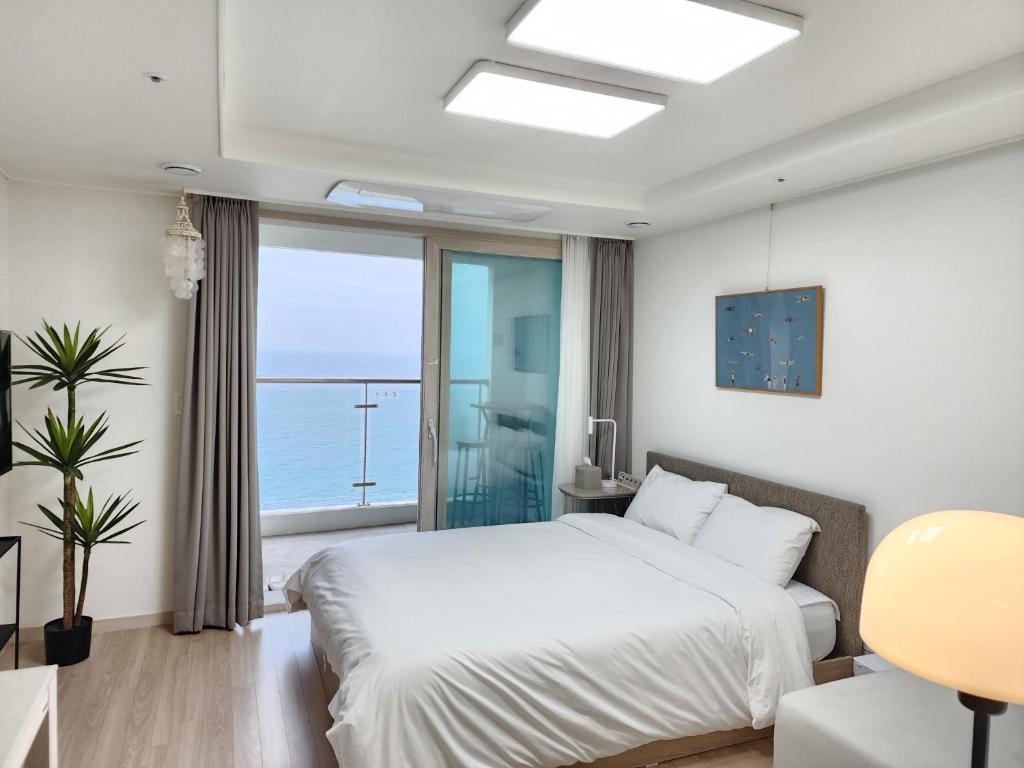 a bedroom with a white bed and a large window at Sokcho Summitbay 1402 "Ocean View" in Sokcho