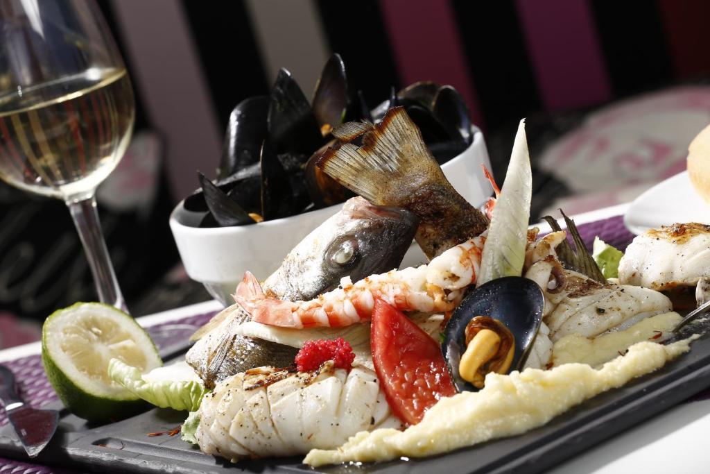 a plate of food with seafood and a glass of wine at Dar El Marsa Hotel & Spa in La Marsa