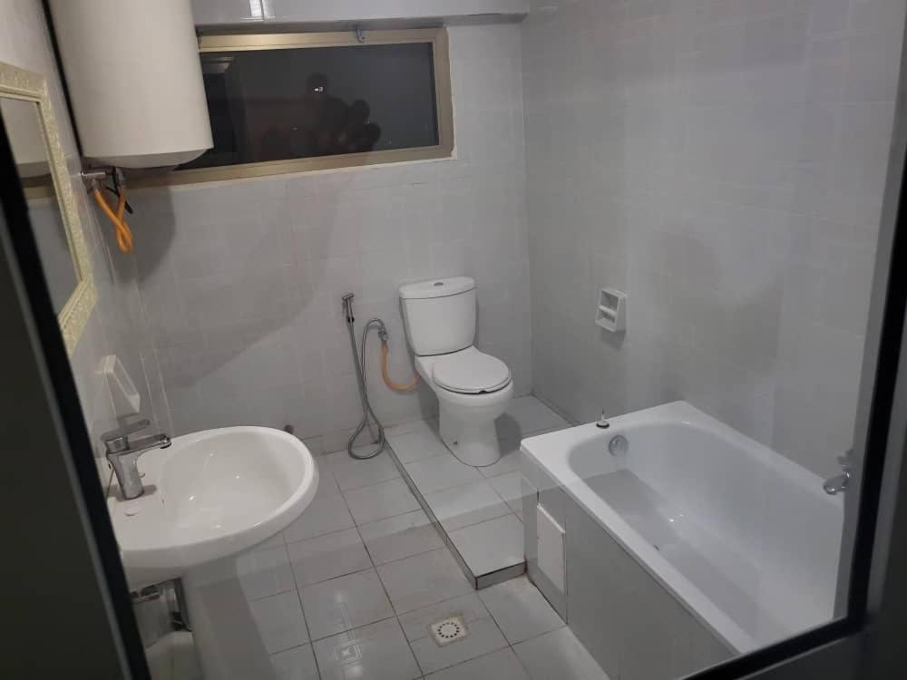 a white bathroom with a toilet and a sink at Hôtel particulier HP in Conakry