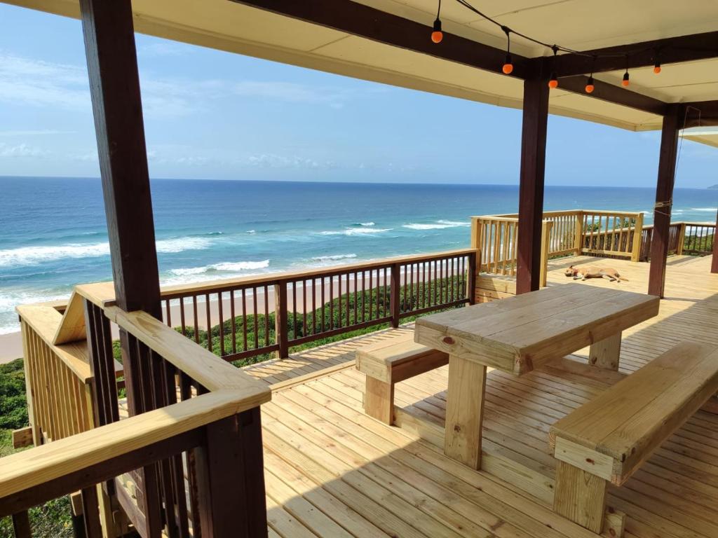 een houten terras met een picknicktafel en de oceaan bij 180° Ocean View Dune House in Chefe Imala