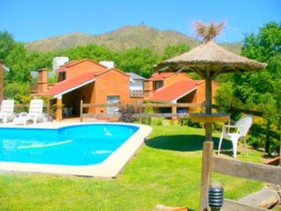 a house with a swimming pool and a umbrella at Chalets Los Abedules in Villa General Belgrano