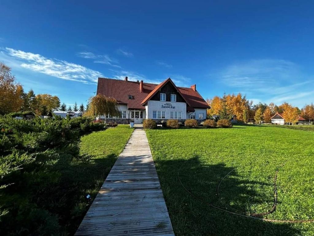 Una pasarela que conduce a una casa en un campo en Pensjonat Żurawi Kąt, en Górkło