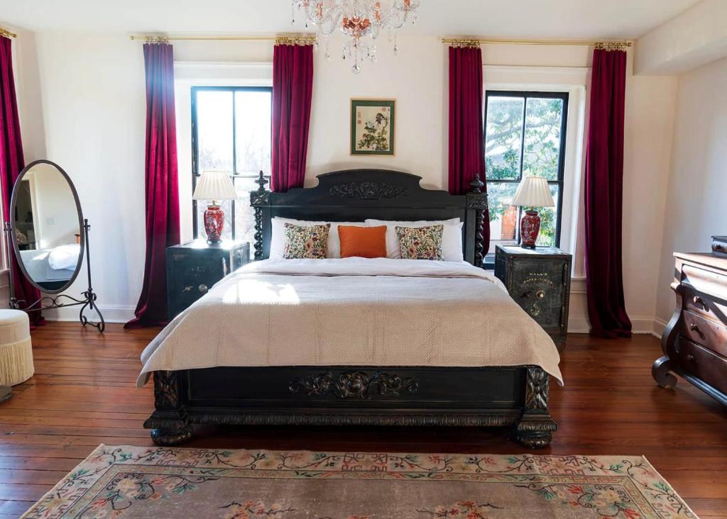 um quarto com uma cama grande e cortinas vermelhas em Yoko's Serene Suite in Frankfort em Louisville